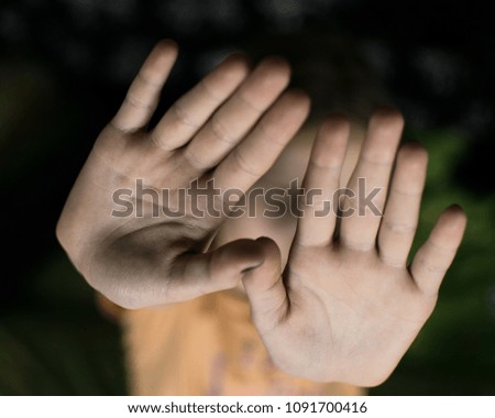 A hand gesture signifying a stop. The girl's palm stretched forward.