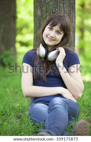Young fashion girl with headphones at green spring grass.