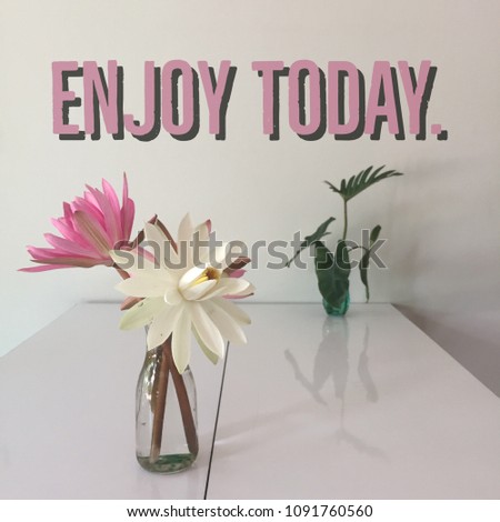 Inspirational motivational quote "enjoy today" with flowers on vase background.