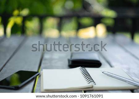 Closeup notebook and pen and smartphone on wooden table use for education and business concept background