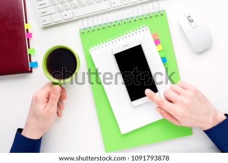 white desk, male hands, man holding Cup of coffee, uses white smart phone, office supplies, white background with copy space, for advertisement, top view