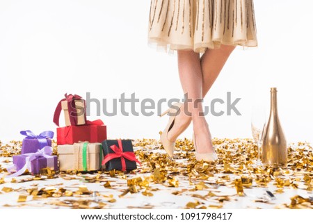 cropped image of woman standing on confetti near gift boxes