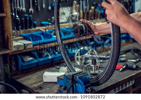 Vintage bicycle repair workshop. Man fixing bicycle parts with a wrench working in garage, service in auto repair station. Bicycle repairing. Royalty-Free Stock Photo #1091802872