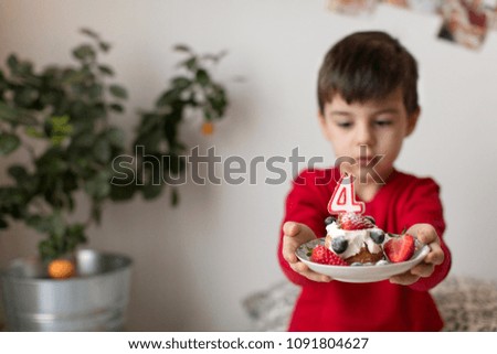 Young boy holding birthday cupcake