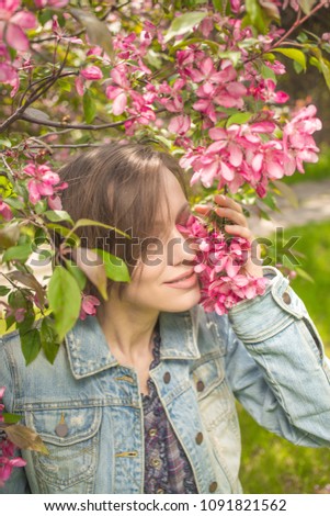 Happy young woman in city park enjoying blooming 