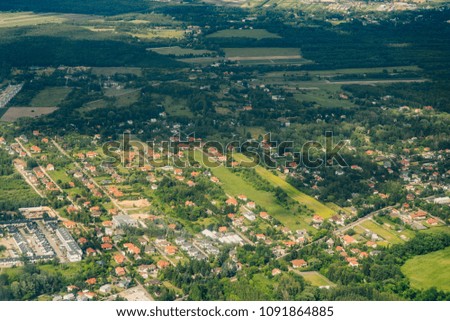 Aerial picture of city with houses and gardens, crossroads and roads, houses, buildings, parks and parking lots, bridges. Airplane drone shot.