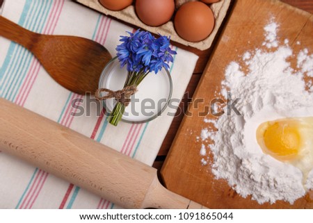 pizza or pie recipe ingridients, food flat lay on wood kitchen table background. baking ingredients. Bowl, eggs, milk, flour, eggbeater, rolling pin and eggshells