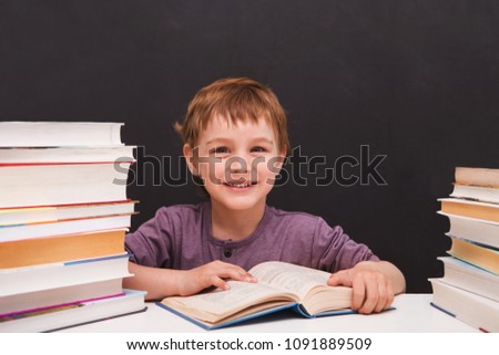 preschooler little boy with books on a black background of a slate board