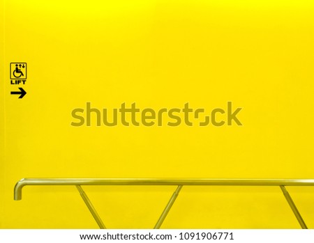 Lift sign for disabled on yellow wall with aluminum handrail