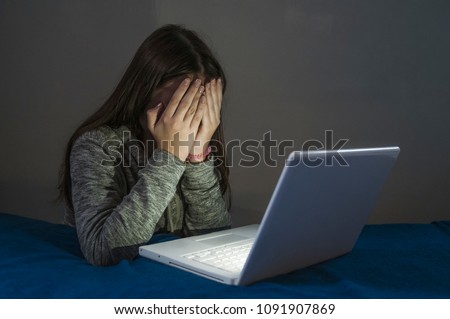 Teenager girl suffering internet cyber bullying scared and depressed cyberbullying. Image of despair girl humilated on internet by classmate. Young teenage girl crying in front of the laptop Royalty-Free Stock Photo #1091907869