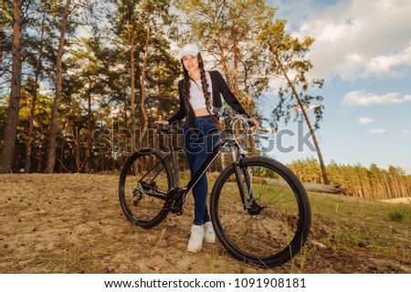 Active life. Sport girl with a bike enjoys the view of sunset over an autumn forest. Heathy lifestyle concept