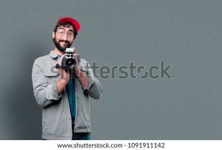 young crazy man with beard and red cap holding a cinema camera. recording concept
