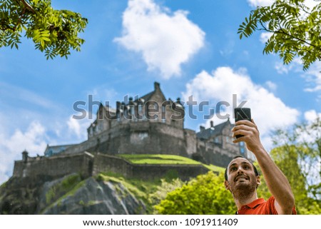 Tourist taking selfie with Edinburgh Castle in spring time.