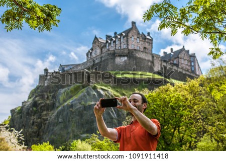 Tourist taking selfie with Edinburgh Castle in spring time.