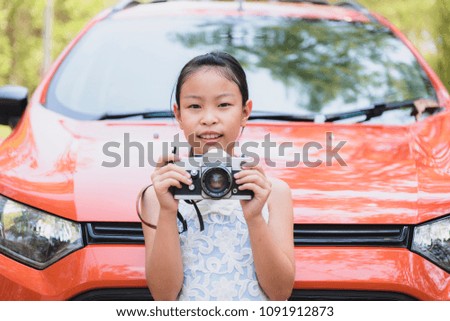 Little girl with an old camera shooting outdoor. Kid taking a photo using a vintage retro film camera. 