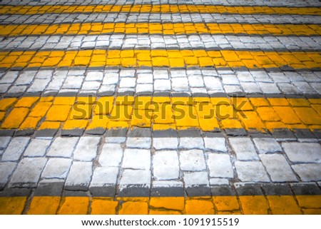The crosswalk of white-yellow color on stone blocks