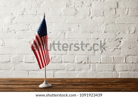 united states of america flagpole on wooden surface against brick wall 