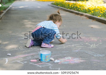 the child paints with chalk on the asphalt