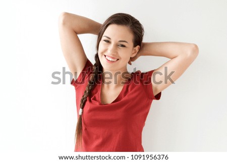 Portrait of happy young woman with hands behind head against white background