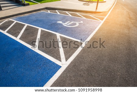 image of blue new handicapped symbol shows sign reserved for disability person on car parking space.