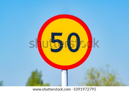 Yellow speed limit sign 50 against the blue sky