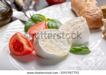 Traditional italian food - white ball mozzarella buffalo Italian soft cheese with cheese knife, tomato, basil, olive oil Royalty-Free Stock Photo #1091987792