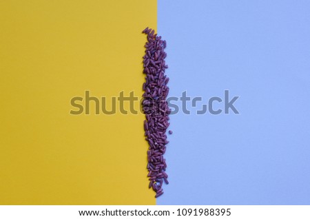 flat lay style photo of a stripe of colorful purple rice with bright colors and texture, laid out between blue and yellow background, child's sensorial play