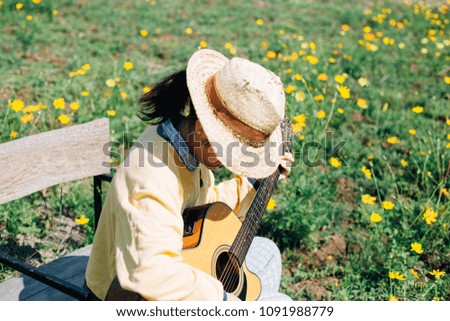 woman play gutar in Tung flowers Cosmos.