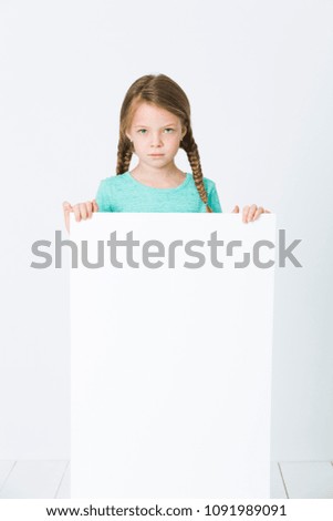 pretty, brunette girl is pointing at white board in front of white background