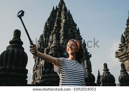 Young tourist woman takin pictures of the amazing Candi Prambanan or Rara Jonggrang, largest Hindu temple site in Indonesia. Yogyakarta, Java. Travel photography.