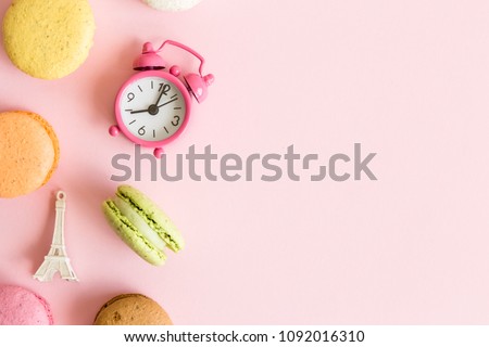 Flat lay of colorful macaroons, small alarm clock and Eiffel Tower French food and culture minimal concept. Space for copy.
