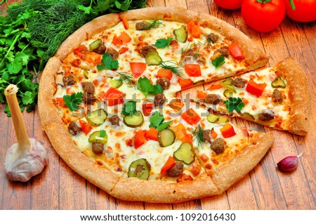 Pizza with meat, cucumbers, tomatoes and greens