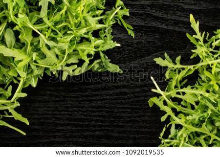 Fresh arugula leaves top view isolated on black wood background

