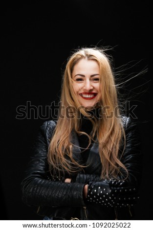 Photo of smiling blonde in leather jacket with arms crossed at waist
