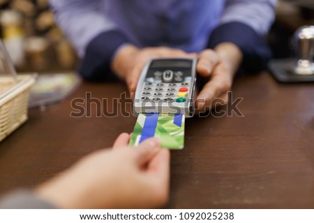 Photo of buyer with bank card and seller with terminal in hand