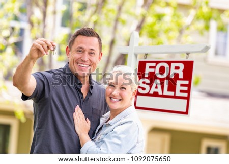 Caucasian Couple in Front of For Sale Real Estate Sign and House with Keys.