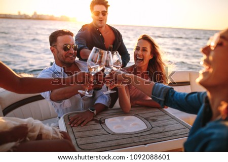 Young people on yacht drinking together. Group of friends toasting drinks and having party on boat. Royalty-Free Stock Photo #1092088601