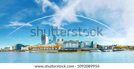Panoramic image of the office block construction on the bank of river Thames in London, under blue sky with feather clouds on a bright day in Autumn