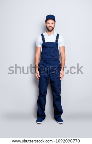Full size fullbody portrait of attractive cheerful deliver in blue uniform with stubble looking at camera holding, isolated on grey background Royalty-Free Stock Photo #1092090770