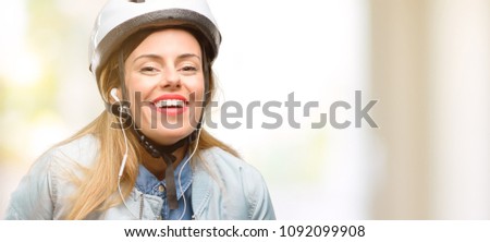 Young woman with bike helmet and earphones confident and happy with a big natural smile laughing