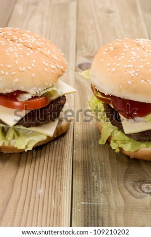 Two Cheeseburger (one double Cheeseburger) on wooden background