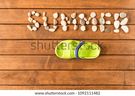 Lettering summer nautical stones on wooden background with  flip flops . The view from the top. The concept of summer.