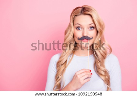 Portrait of funky foolish  big eyed girl holding black carton mustache on stick in hand looking at camera isolated on pink background Royalty-Free Stock Photo #1092150548