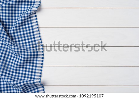 Blue checkered tablecloth on an old wooden table. Close up