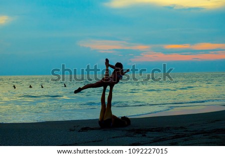 Couple practice yoga on the beach at sunset. 