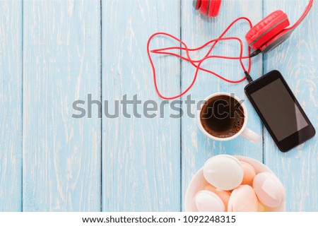 the marshmallow is next to the phone and red headphones and a Cup of black coffee. Coffee-break. Pleasant music.