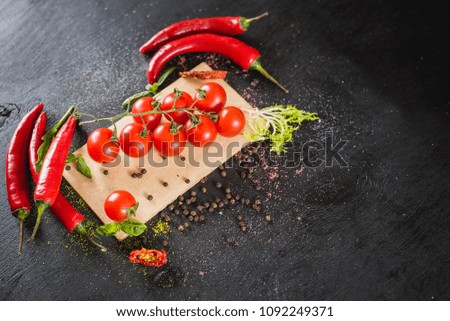 Fresh raw vegetables with different spices on black wooden background. Top view. Copy space.