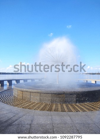 Fountain in the form of a ball on the river, a view of the waterfront with a blue sky, a landscape with a fountain and a river. Copy space