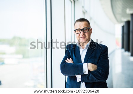 Closeup of a senior businessman with his arms folded in an office interior.