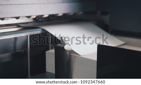 Printing press machine takes sheet of paper in action in the printing production line Royalty-Free Stock Photo #1092347660